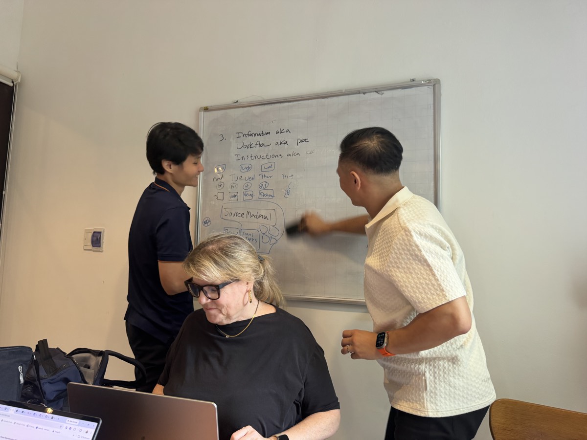 An engineer and a guest mapping a workflow on the whiteboard